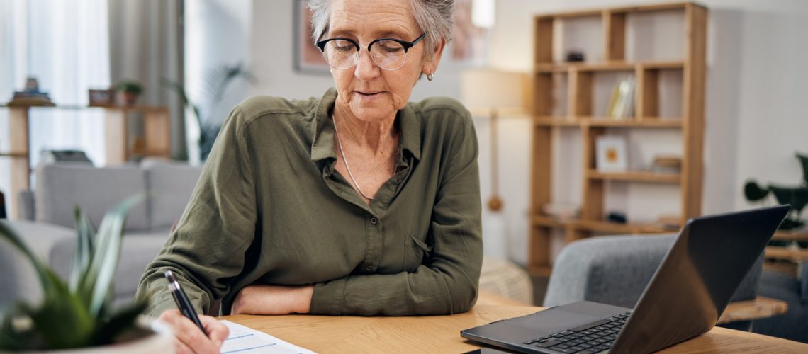 Focus, writing and senior woman for asset management, planning and paperwork of financial investment. Insurance, budget ideas or taxes on laptop of boss, executive or entrepreneur in home living room
